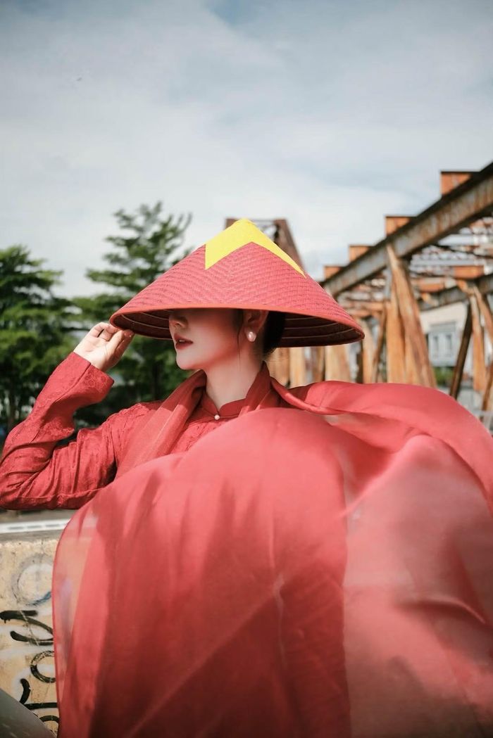 Huyền Lizzie diện áo dài đỏ, cầm cờ Tổ quốc và đội nón in hình cờ đỏ sao vàng mừng ngày Quốc khánh 2/9.