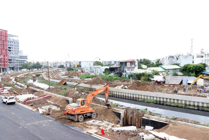 Bờ trái đã khang trang nhưng việc hoàn thiện vỉa hè, cây xanh, chiếu sáng vẫn tiếp tục được nhà thầu gấp rút thực hiện sau ngày thông xe. Cùng lúc đó, công trường phía bờ phải cũng đang tăng tốc thi công để đảm bảo mục tiêu thông xe vào cuối tháng 11/2026. Ảnh: TK