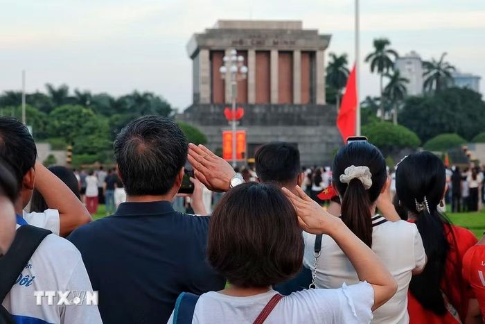 Nhân dân thực hiện nghi thức chào cờ, hướng về Lăng Chủ tịch Hồ Chí Minh trong thời khắc Quốc ca vang lên hùng tráng trên Quảng trường Ba Đình. (Ảnh: Phạm Tuấn Anh/TTXVN)