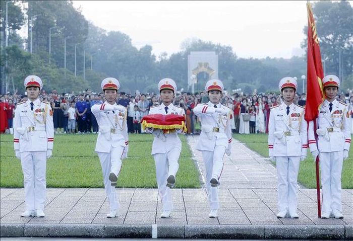 Ba chiến sĩ mang Quốc kỳ tiến về phía cột cờ chuẩn bị thực hiện nghi Lễ Thượng cờ. Ảnh: Phạm Kiên/TTXVN