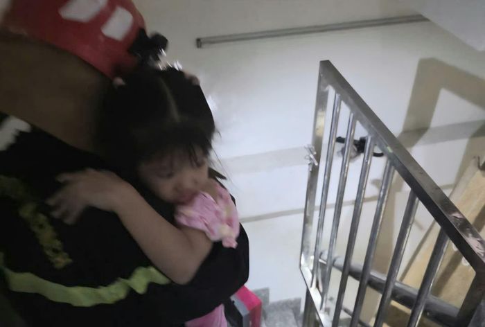 Người lớn và em nhỏ được lực lượng PCCC giải cứu ra ngoài. Ảnh: CTV