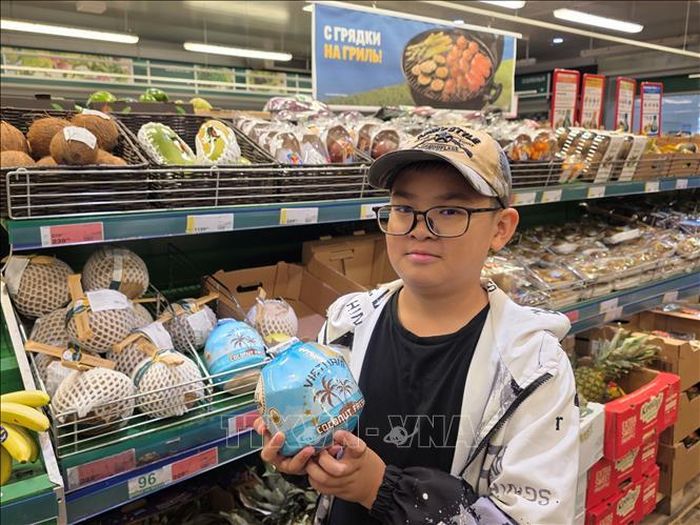 Một khách hàng châu Á với mặt hàng dừa có ống hút của Việt Nam.