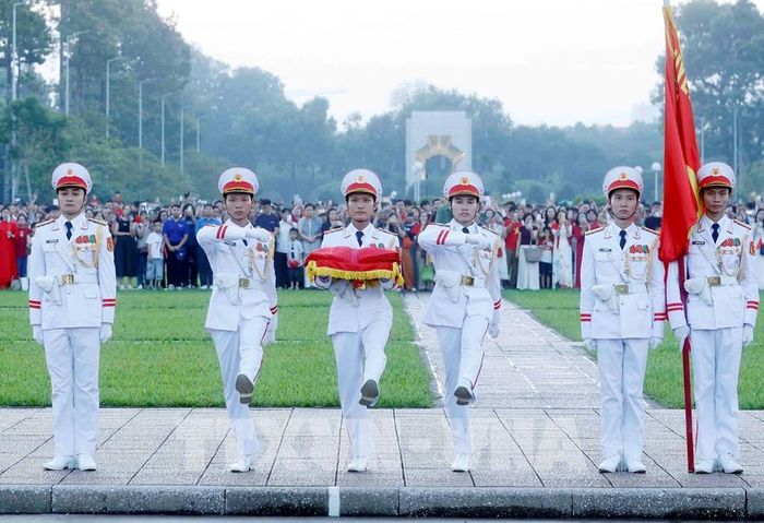 Ba chiến sĩ mang Quốc kỳ tiến về phía cột cờ chuẩn bị thực hiện nghi Lễ Thượng cờ. Ảnh: Phạm Kiên – TTXVN