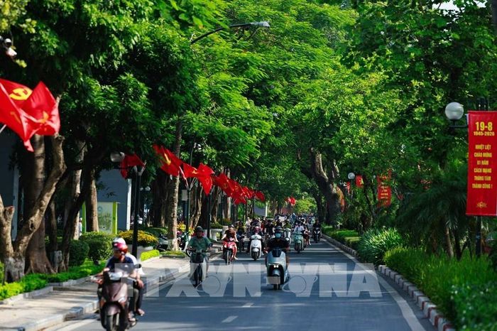 Cờ Đảng, cờ Tổ quốc nối dài giữa những hàng cây, hòa cùng dòng người qua lại, khiến không khí ngày Tết Độc lập hiện diện ngay trong nhịp sống thường nhật của Hà Nội. Ảnh: Phạm Tuấn Anh - TTXVN