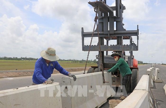 Công nhân thuộc Tổng Công ty Xây dựng Trường Sơn tăng ca làm xuyên lễ nhằm lắp đặt, hoàn thiện hệ thống dải phân cách. Ảnh: Công Mạo-TTXVN