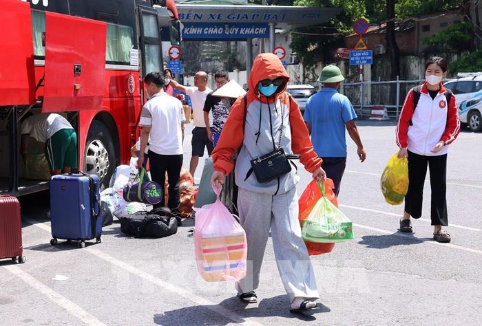 Người dân vội vã trở về nhà với đồ đạc lỉnh kỉnh trên tay tại bến xe Giáp Bát. Ảnh: Quốc Khánh - TTXVN 