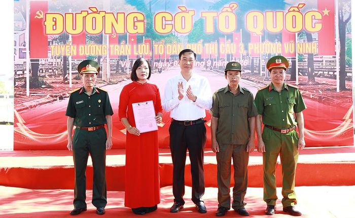  Đồng chí Nguyễn Hoàng Long, Bí thư Đảng ủy phường Vũ Ninh trao Quyết định thành lập mô hình "Đường cờ Tổ quốc" cho Ban Chủ nhiệm mô hình. 