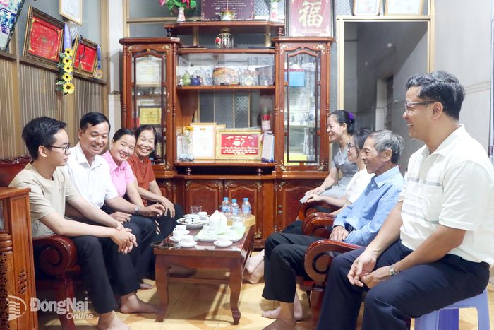 Phó Bí thư chi bộ, Trưởng khu phố 11, phường Long Bình Đàm Văn Nhượng (thứ hai bên trái) và Trưởng ban Công tác Mặt trận khu phố 11 Chu Thị Trinh (thứ ba bên trái) trò chuyện cùng đại gia đình 3 thế hệ cựu chiến binh Nguyễn Văn Nhuận. Ảnh: PV