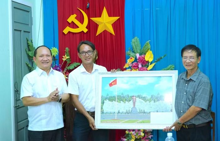 Phó Bí thư Thường trực Tỉnh ủy Rah Lan Chung (bìa trái) tặng bức ảnh Tượng đài Bác Hồ với các dân tộc Tây Nguyên tại Quảng trường Đại Đoàn Kết (phường Pleiku) cho Chi bộ tổ dân phố 1 (Hải Minh, phường Quy Nhơn) trong dịp đến dự sinh hoạt chi bộ thường kỳ tháng 8-2026 tại đây. Ảnh: N.H