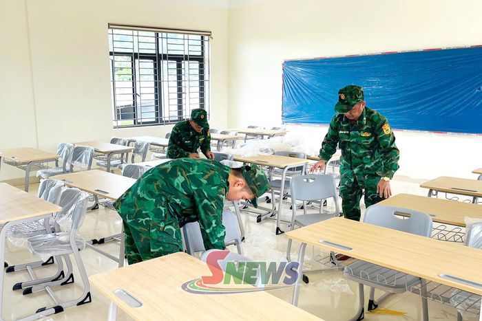 Cán bộ, chiến sĩ Đồn Biên phòng Mường Cai hỗ trợ vệ sinh lớp học và lắp đặt trang thiết bị giảng dạy.