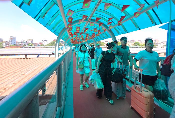 Hành khách trên cầu vượt đường bộ trong ga di chuyển ra cửa ga.