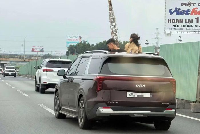 Hình ảnh 2 trẻ em thò đầu ra cửa sổ trời khi ô tô đang chạy trên cao tốc.