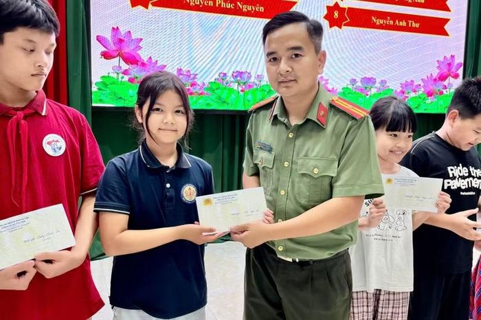 Đồng chí Nguyễn Anh Quang, Phó trưởng Công an xã Ứng Hòa trao phần thưởng động viên thế hệ trẻ trước thềm năm học mới.