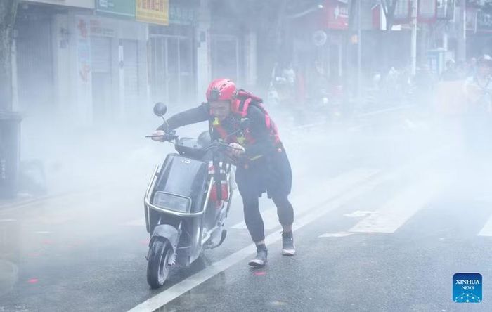 Nhân viên cứu hộ di chuyển chiếc xe đạp điện bị bốc cháy sau khi đi qua vùng nước lũ ở thành phố Phúc An, tỉnh Phúc Kiến ngày 2-9-2026