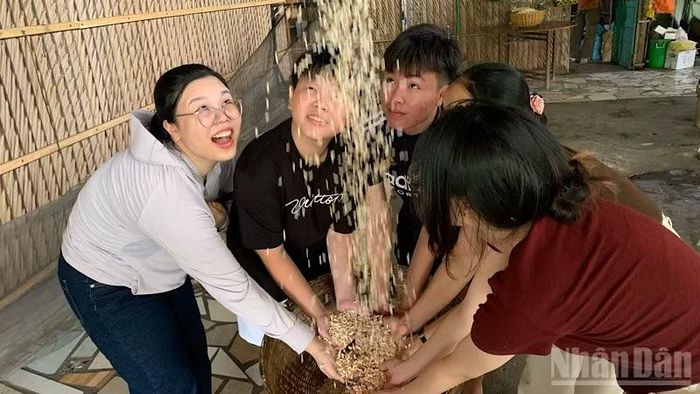 Du khách trải nghiệm nghề làm cốm. (Ảnh: THANH TÂM)