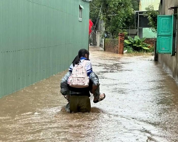 Lực lượng chức năng cõng các em nhỏ ra khỏi vùng ngập