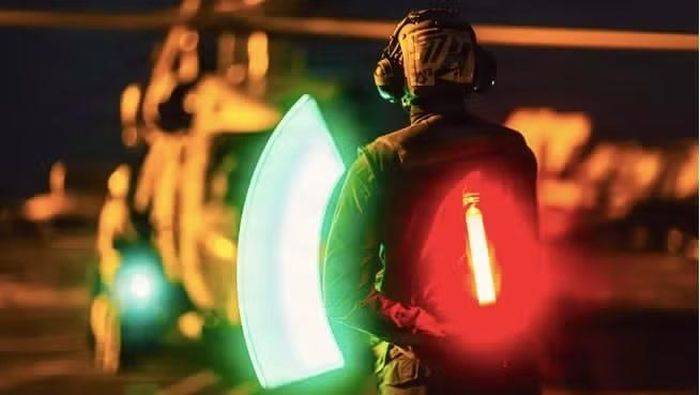 Thuỷ thủ Mỹ ra hiệu cho chiếc MH-60R Seahawk thuộc Phi đội Trực thăng tấn công hàng hải 77 trên sàn tàu sân bay USS George Washington ngày 25/8
