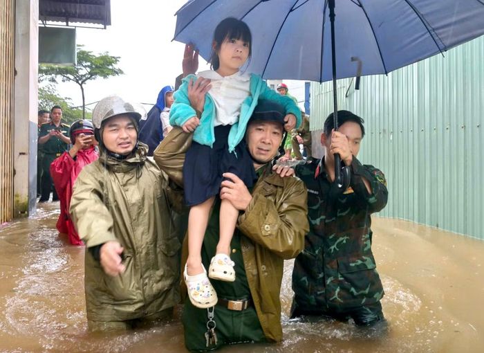 Một bé gái được lực lượng chức năng bế qua vùng nước nguy hiểm, đưa về nhà.
