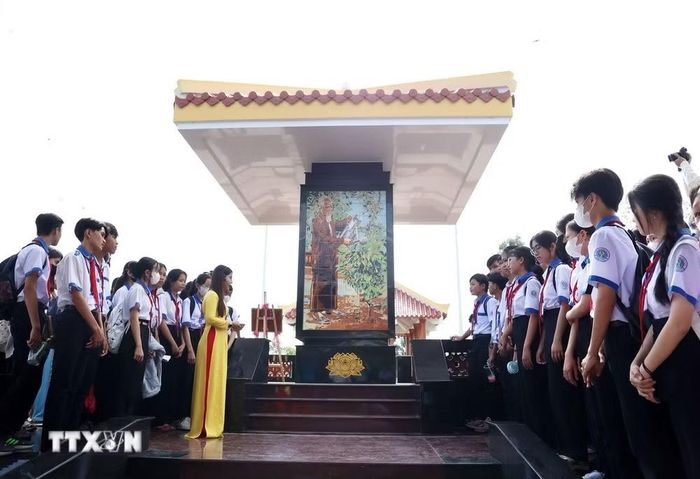 Học sinh ôn lại sự kiện lịch sử 70 năm tập kết ra Bắc trên quê hương Cà Mau trước Bia kỷ niệm Bác Hồ với cây vú sữa miền Nam. (Ảnh: Hồng Đạt/TTXVN)
