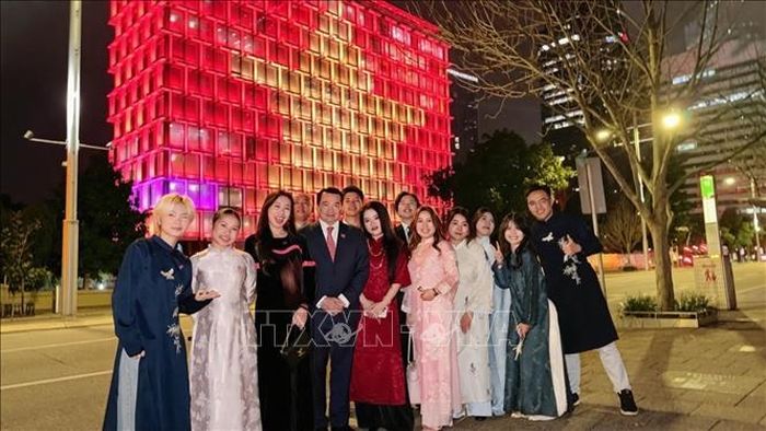 Cán bộ Tổng lãnh sự quán Việt Nam tại Perth chụp ảnh lưu niệm với hình ảnh Quốc kỳ Việt Nam được thắp sáng trên Toà thị chính Perth. Ảnh: TTXVN phát