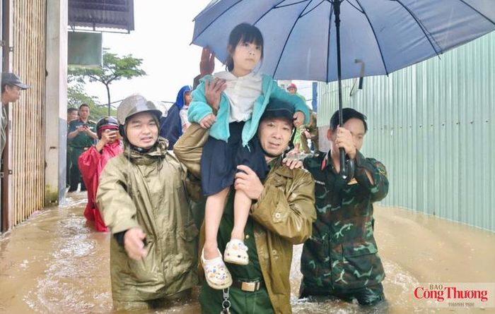 Lực lượng chức năng hỗ trợ đưa các em nhỏ di chuyển khỏi khu vực ngập sâu.
