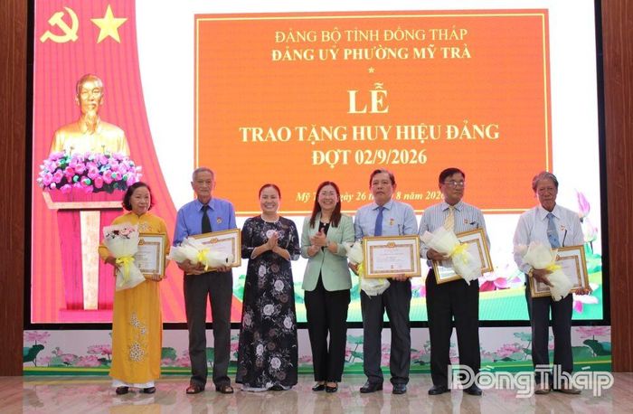 Đồng chí Trần Thị Quý, Tỉnh ủy viên, Bí thư Đảng ủy, Chủ tịch HĐND phường Mỹ Trà (thứ 3 từ trái sang) và đồng chí Đỗ Thị Thanh Trang, Phó Trưởng Ban Tổ chức Tỉnh ủy, trao Huy hiệu Đảng, tặng hoa chúc mừng các đảng viên.