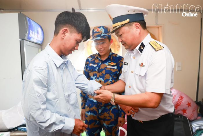Đại tá Bùi Xuân Bình hỗ trợ ngư dân Trần Văn Thuận thay áo.