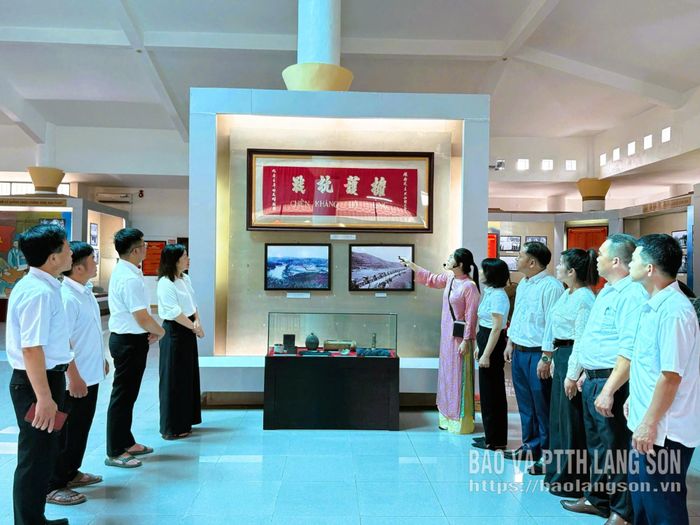 Thuyết minh viên Bảo tàng tỉnh giới thiệu cho khách tham quan về các tư liệu ảnh, hiện vật lịch sử tại nhà trưng bày