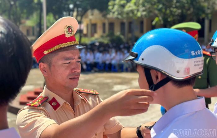 Lực lượng Cảnh sát giao thông Công an tỉnh hướng dẫn các em đeo mũ bảo hiểm đúng quy định.