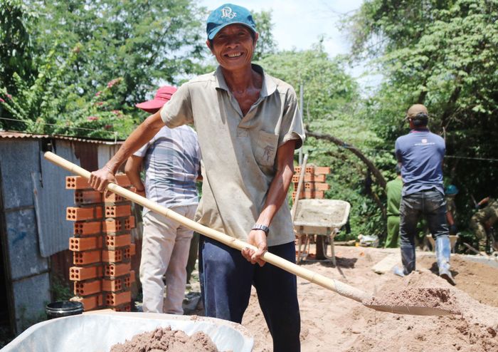 Ông Dũng xúc cát cùng mọi người xây nhà cho gia đình mình