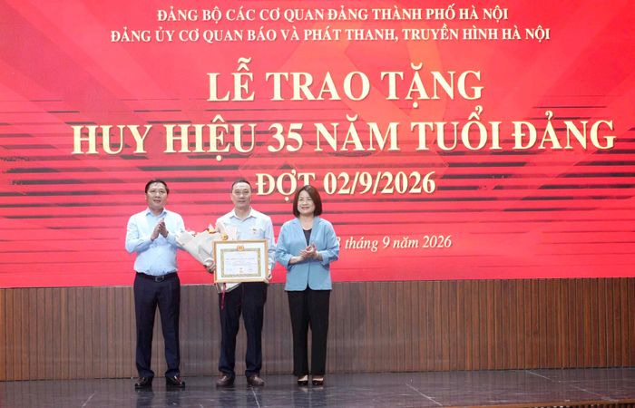 Phó Bí thư Đảng ủy các cơ quan Đảng thành phố Hà Nội Phạm Thị Nguyên Hạnh và Thành ủy viên, Bí thư Đảng ủy, Giám đốc Cơ quan Báo và Phát thanh, Truyền hình Hà Nội Nguyễn Thanh Liêm trao Huy hiệu 35 năm tuổi Đảng và tặng hoa chúc mừng đảng viên Nguyễn Thanh Luận. Ảnh: Phạm Hùng