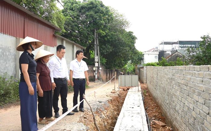 Bà Phùng Thị Lộng (thứ 2 từ trái qua) cùng đại diện chính quyền địa phương bên phần diện tích đất gia đình tự nguyện hiến tặng mở rộng tuyến đường ngõ 77A. Ảnh Đ. Đạt