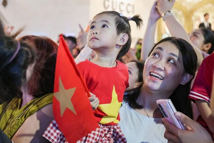 Các em nhỏ được bố mẹ bế/cõng lên, chăm chú hướng mắt về phía bầu trời, theo dõi những màn pháo hoa rực rỡ. (Ảnh MĐ)
