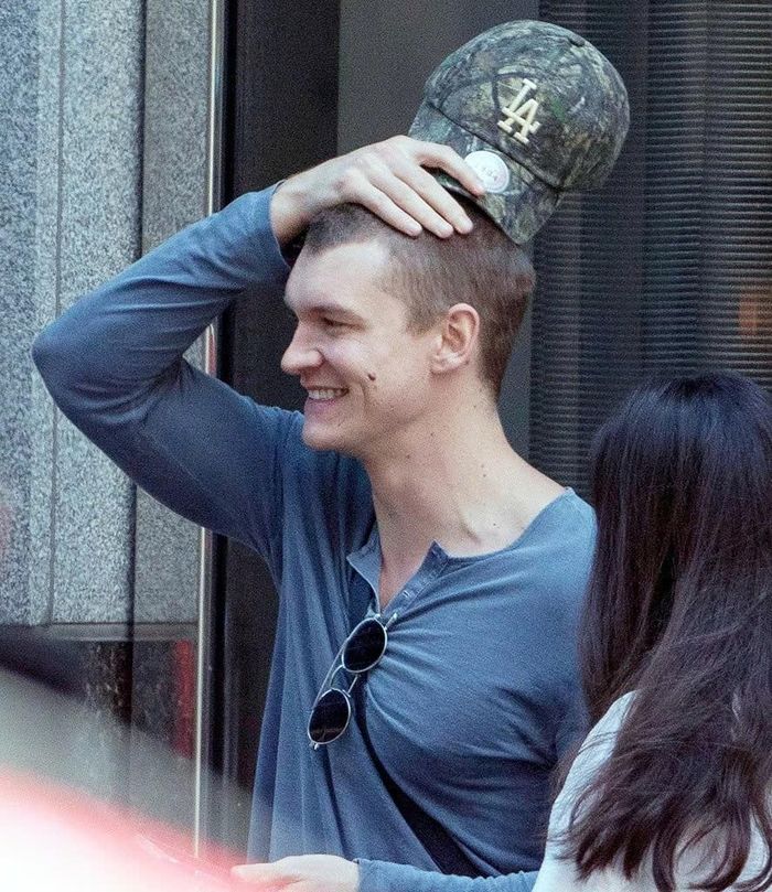  Connor Storrie giấu mái tóc húi cua dưới chiếc mũ rằn ri trong loạt ảnh được báo chí ghi lại tại phim trường Heated Rivalry. Ảnh: Backgrid. 