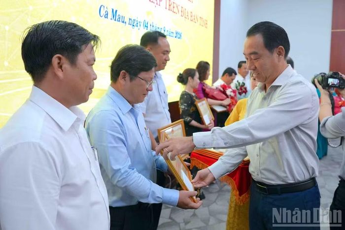 Phó Bí thư Tỉnh ủy, Chủ tịch Ủy ban nhân dân tỉnh Cà Mau Lữ Quang Ngời (bìa phải) tặng Bằng khen cho các tập thể, cá nhân có thành tích xuất sắc trong sắp xếp trường, lớp. (Ảnh: HỮU TÙNG)