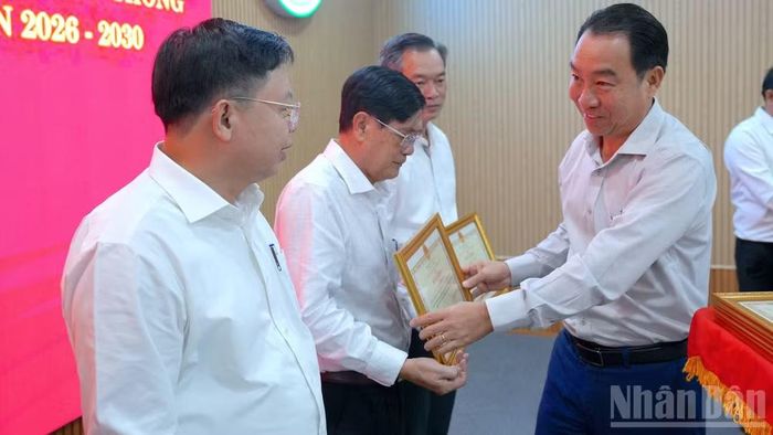Phó Bí thư Tỉnh ủy, Chủ tịch Ủy ban nhân dân tỉnh Cà Mau Lữ Quang Ngời (bìa phải) tặng Bằng khen cho các tập thể, cá nhân có thành tích xuất sắc trong công tác hỗ trợ xây dựng nhà. (Ảnh: HỮU TÙNG)