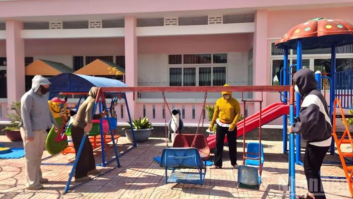 Tập thể cán bộ, giáo viên Trường mầm non Bình Hòa sắp xếp trang thiết bị vui chơi cho trẻ em.