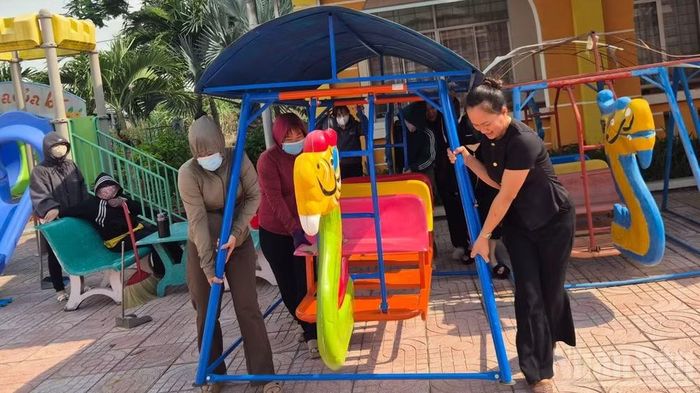 Tập thể cán bộ, giáo viên Trường mầm non Bình Hòa sắp xếp trang thiết bị vui chơi cho trẻ em.