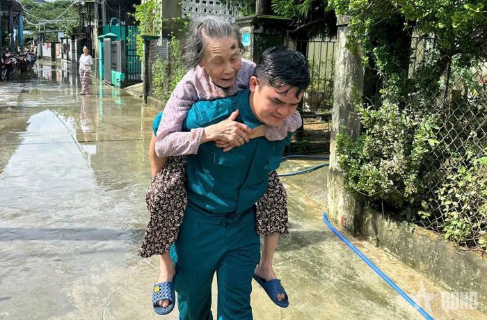 Tiểu đội trưởng Dân quân cơ động Huỳnh Ngọc Hùng cõng Bà mẹ Việt Nam anh hùng Bùi Thị Lại trong đợt tránh bão Kalmaegi hồi tháng 11-2025. 