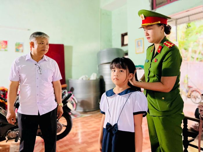 Nữ chiến sĩ Công an xã Thu Bồn mặc bộ đồ đồng phục cho bé Khánh Ngân.