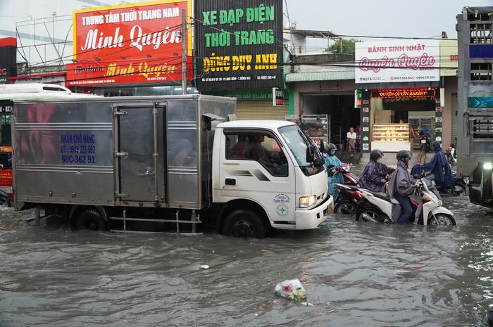 Nước ngập lênh láng, dòng phương tiện di chuyển chậm. Ảnh: PHÚ NGÂN