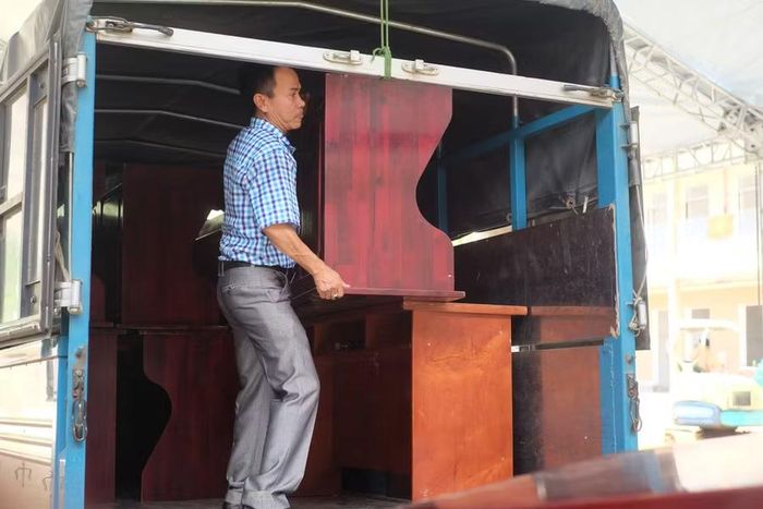 Ông Trần Hữu Nhất, Phó Hiệu trưởng Trường Phổ thông nội trú Tiểu học & THCS A Vương bưng bàn ghế để đưa vào các phòng chức năng.