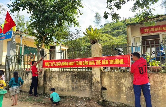 Giáo viên ở Điểm trường Sài Khao - Trường Tiểu học Mường Lý treo băng zôn.