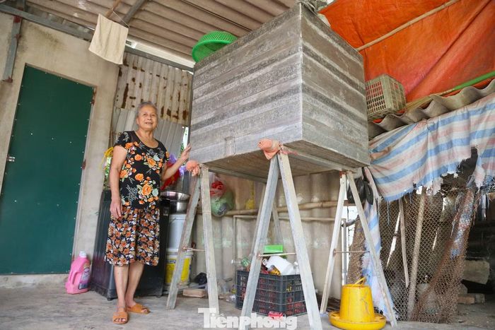 Mỗi dịp gần mùa mưa bão, gia đình bà Nguyễn Thị Hưng (75 tuổi, xóm Hưng Lợi 2, xã Lam Thành) lại tất bật kê cao tài sản, lương thực. Chiếc thùng tôn cao khoảng 2m được bà tận dụng để bảo quản lúa. Cùng con gái, bà cẩn thận khiêng từng bao lúa cho vào thùng, tránh ẩm mốc khi nước lũ tràn vào nhà. Phía trên nắp thùng, một số vật dụng khác cũng được đặt lên để tránh nước.