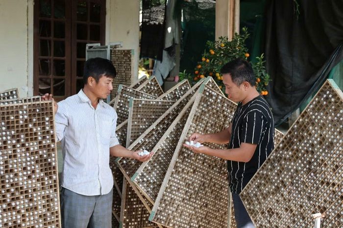 Anh Tôn Long Quý (phải) trò chuyện cùng người nuôi tằm lấy kén.