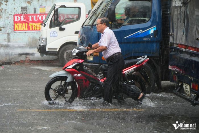 Đi qua đoạn đường ngập sâu, xe của người đàn ông bị chết máy. Ông phải dắt bộ xe đi qua khu vực ngập sâu trên Quốc lộ 1.