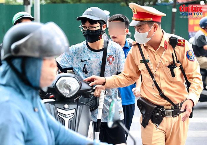 Một học sinh cùng phương tiện được cán bộ Cảnh sát giao thông hướng dẫn vào khu vực kiểm tra.