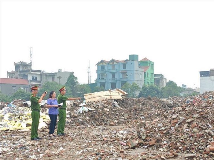 Cơ quan điều tra phối hợp với các đơn vị chuyên môn tiến hành khám nghiệm hiện trường, xác định diện tích và khối lượng chất thải xây dựng bị đổ trái phép. Ảnh: TTXVN phát