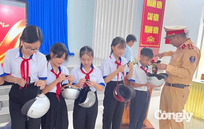 CSGT tuyên truyền, hướng dẫn học sinh đội mũ bảo hiểm đúng cách.