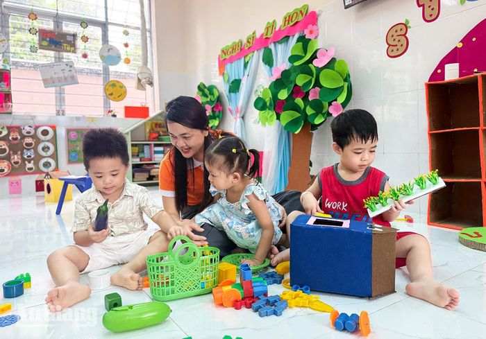 Cô Lê Thị Thùy Linh, giáo viên lớp mầm 1 Trường Mầm non Bình Minh, phường Rạch Giá chơi cùng trẻ trong ngày tựu trường năm học 2026 - 2027. Ảnh: BÍCH TUYỀN